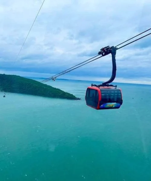 Vietnam tour package adventure with scenic cable car ride over turquoise ocean and lush green island landscape.