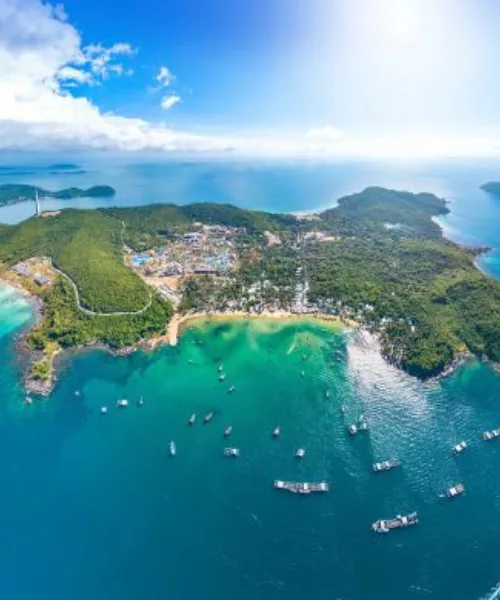 Vietnam tour package showcasing aerial view of tropical island, emerald bays, boats, and coastal town in Vietnam.